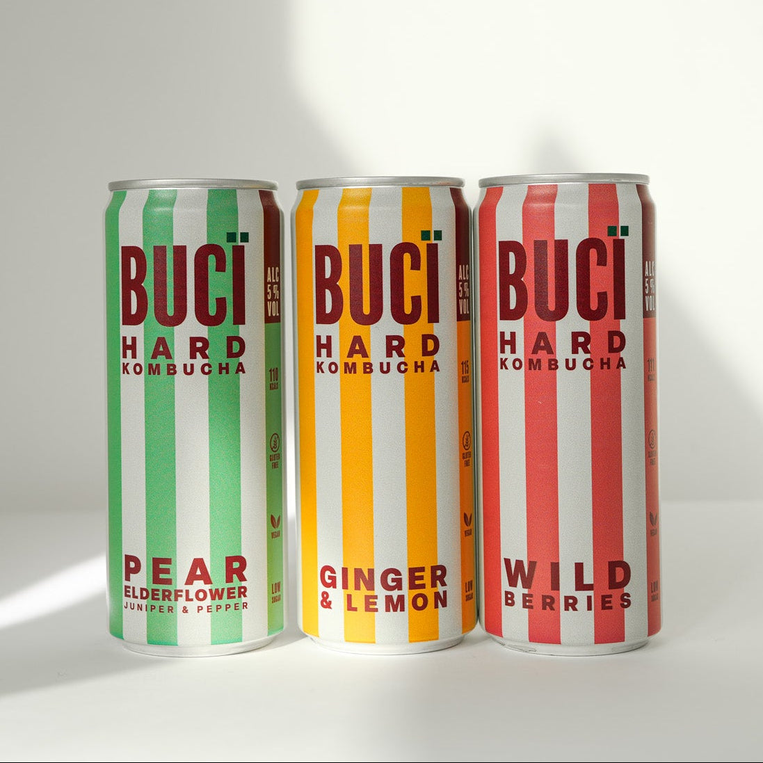 Three cans of BUCÏ Hard Kombucha lined up next to each other.