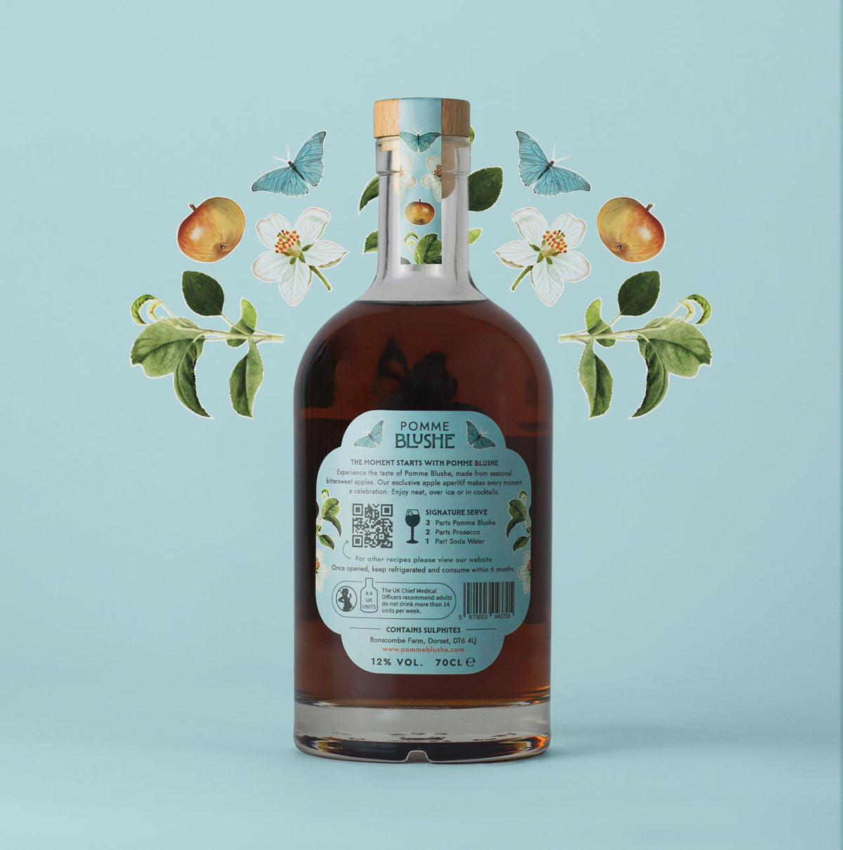 A bottle of Pomme Blushe apple aperitif with an illustration of apples and leaves in the background.