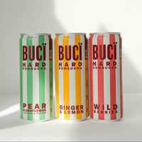 Three cans of BUCÏ Hard Kombucha lined up next to each other.