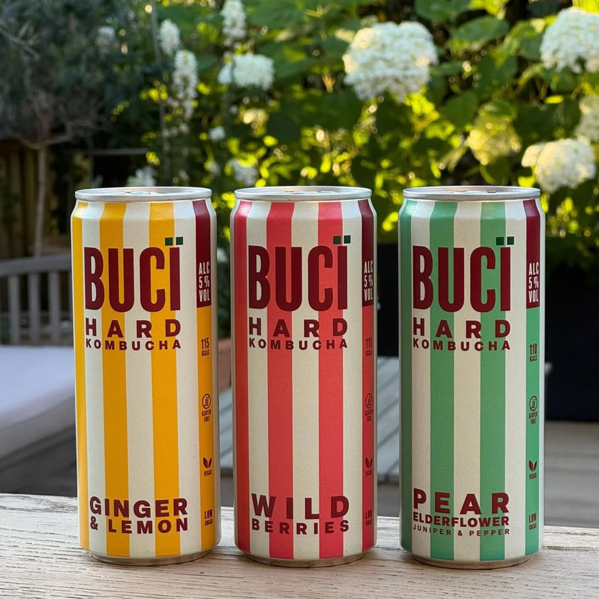 Three cans of BUCÏ Hard Kombucha sat next to each other on a table.