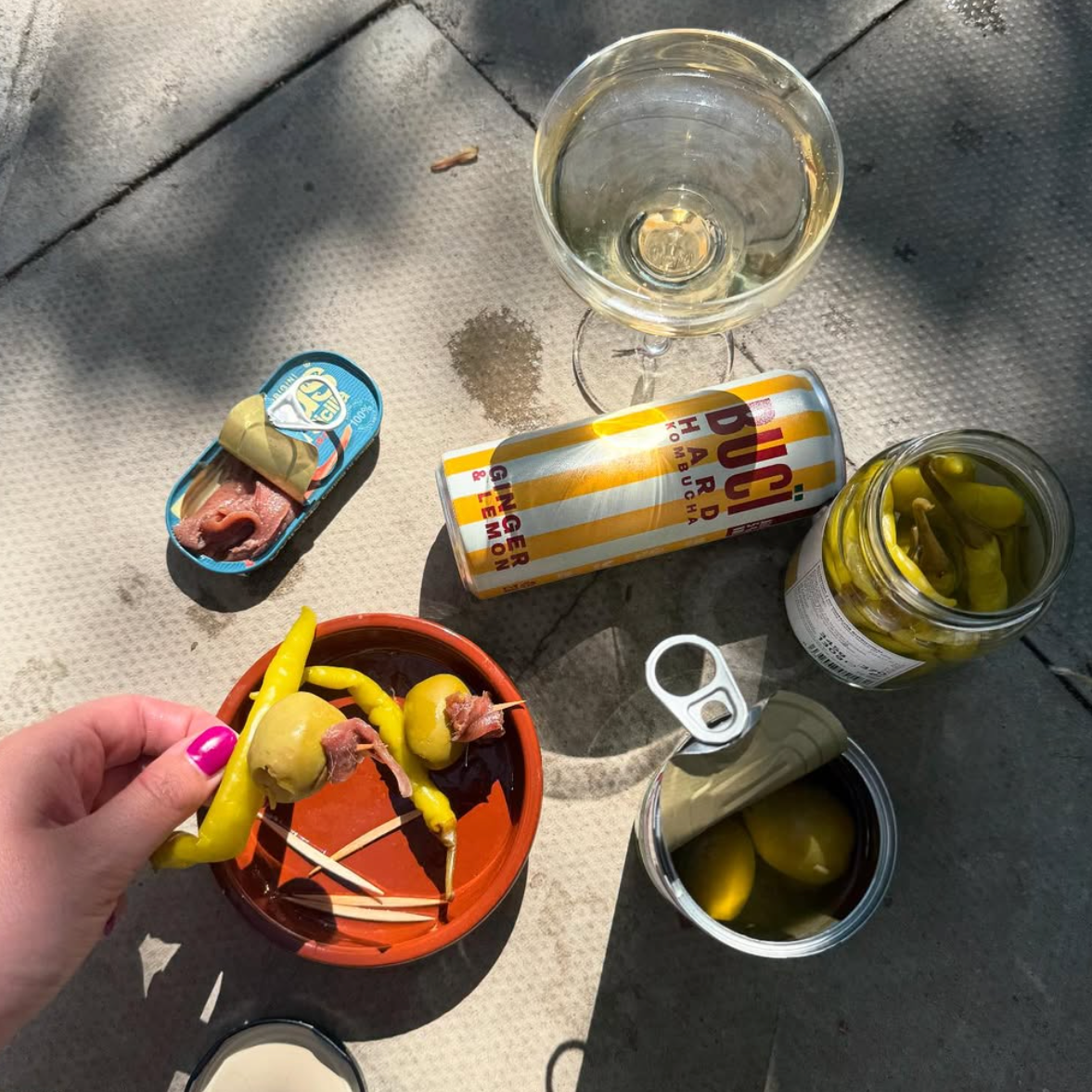 A can of BUCÏ Lemon and Ginger Hard Kombucha on a floor next to various foods.