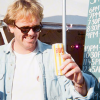 A man wearing sunglasses holding a can of BUCÏ Lemon and Ginger Hard Kombucha.