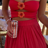 Person wearing a red dress with floral details holding a can of BUCÏ Wild Berries Hard Kombucha.