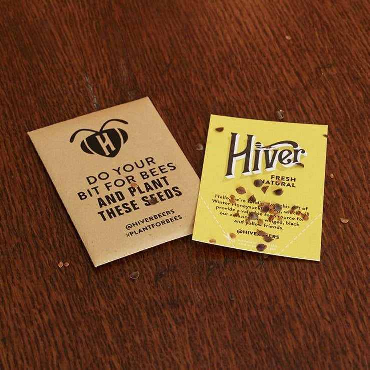 Two Hiver seed packet cards with wildflower seeds scattered on a wooden table