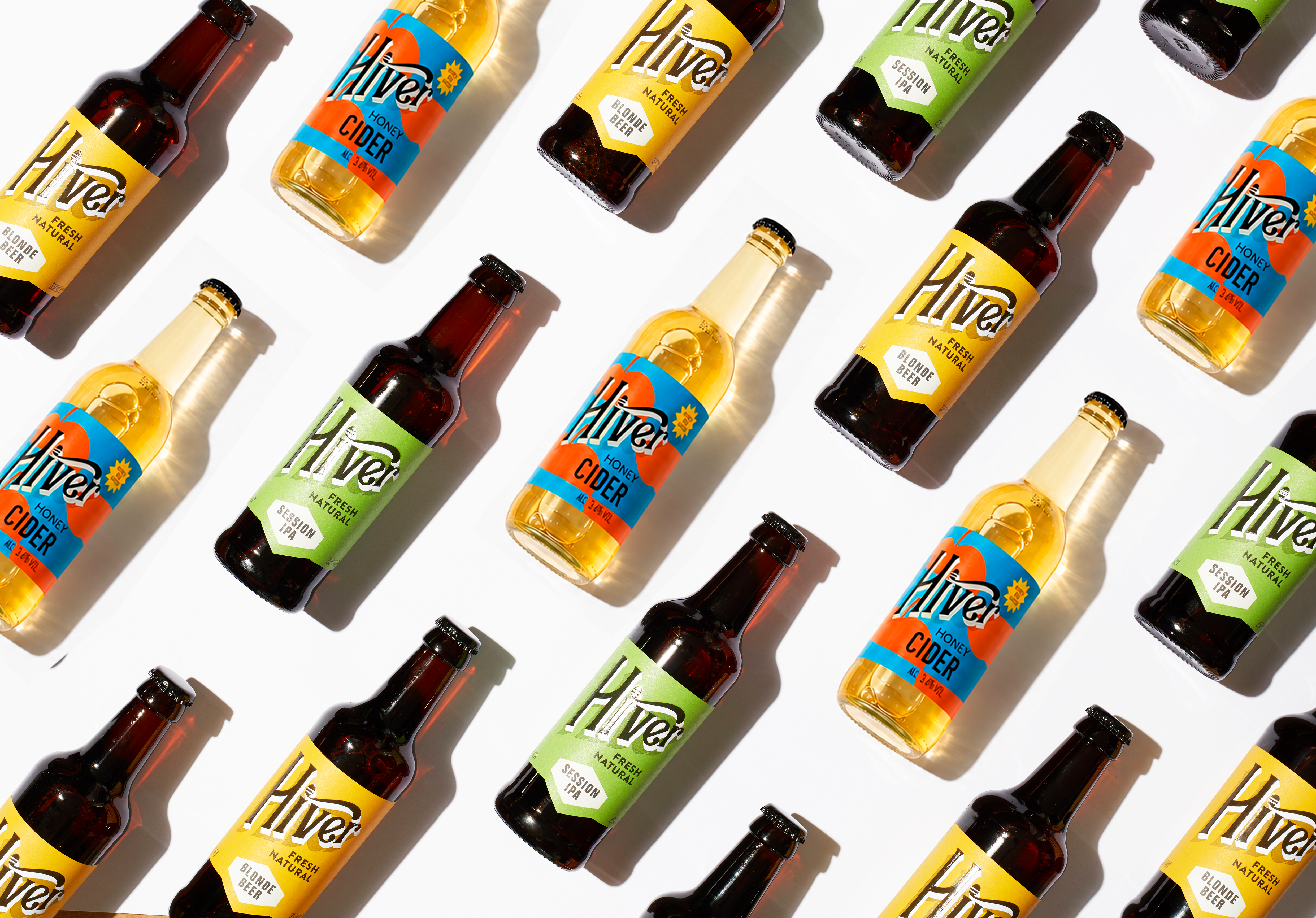 Bottles of Hiver Honey Cider, Session IPA and Blonde Beer arranged diagonally on a white background